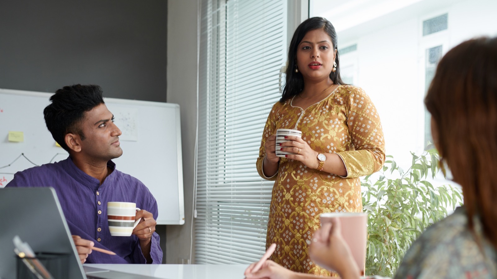 Three colleagues in discussion at a whiteboard during a working session